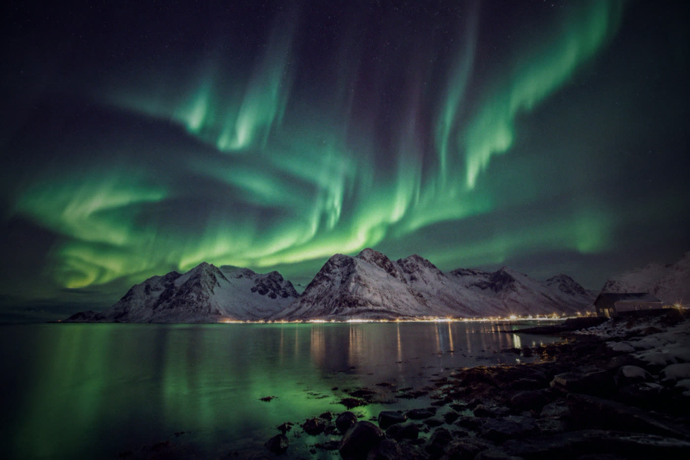 Northern lights over snow-covered mountains and a fjord at Senja
