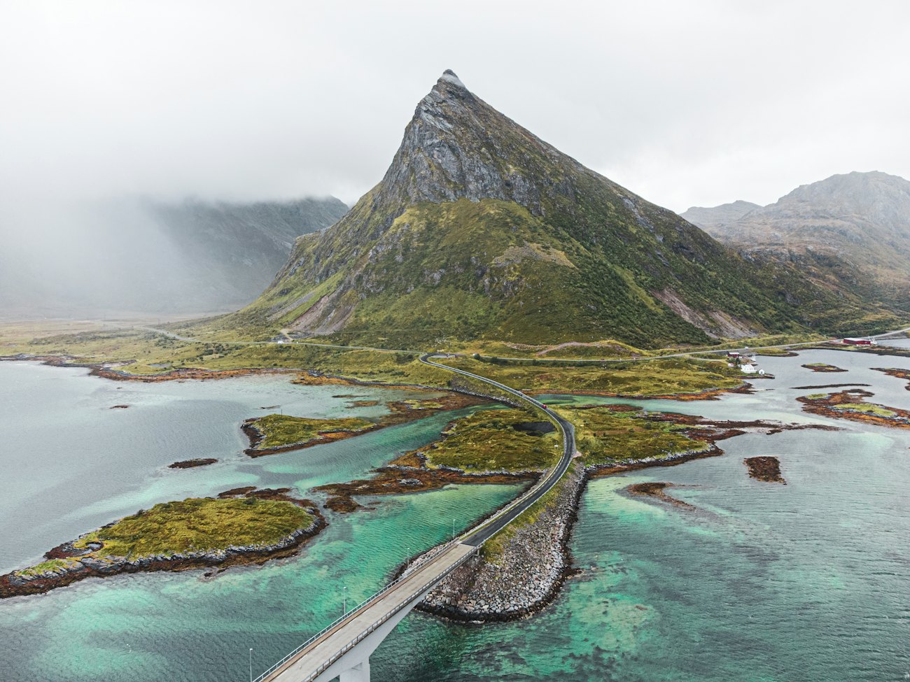 The Fredvang bridges curving across turquoise shallows toward a pointed green mountain