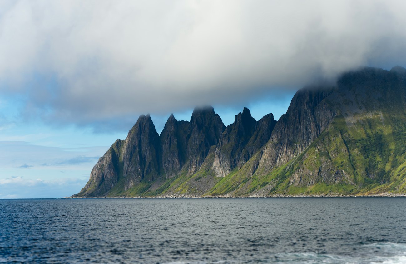 The serrated ridge of Okshornan rising from the sea under low cloud