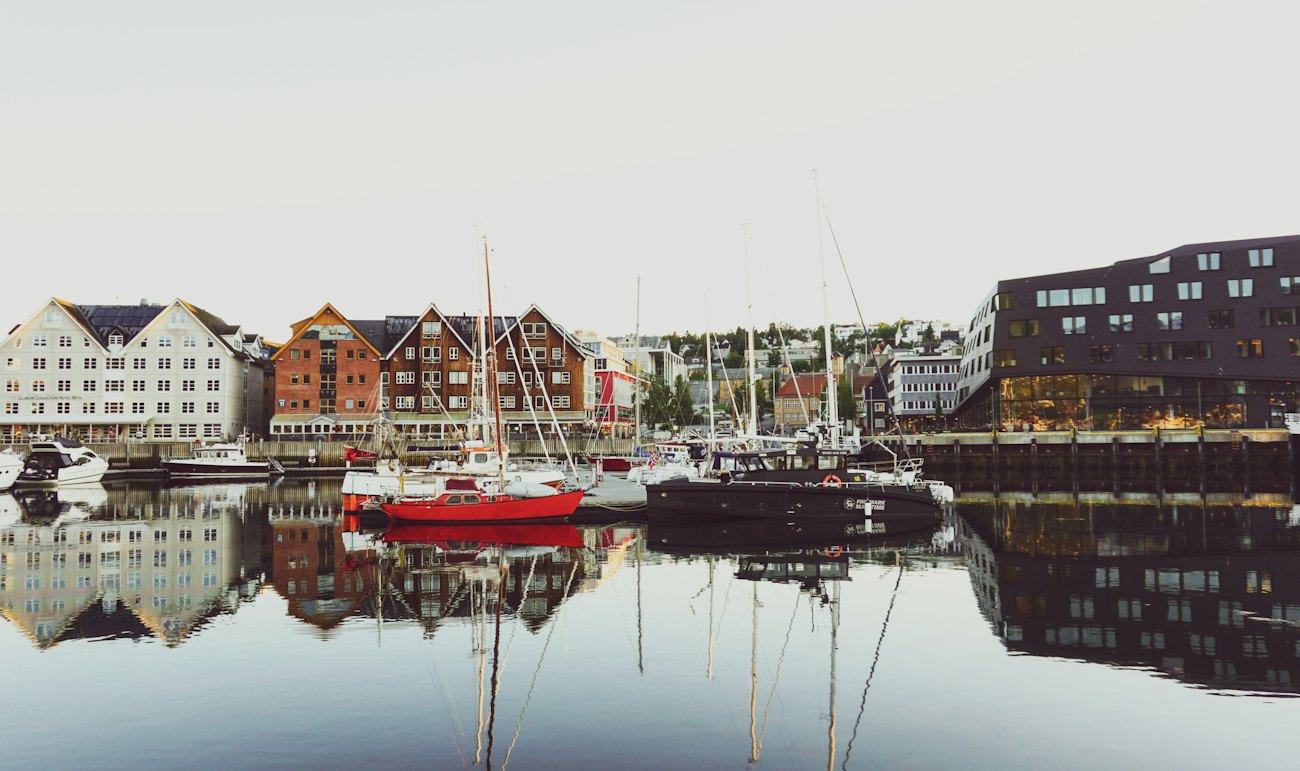 Sailing boats and old wharf houses mirrored in the still water of Tromsø harbour