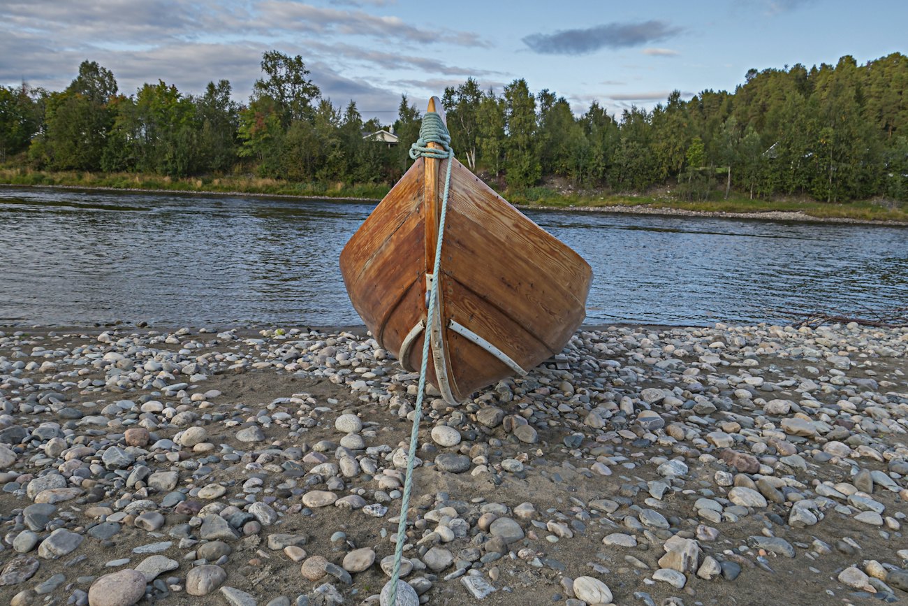A traditional wooden boat pulled up on a pebble beach