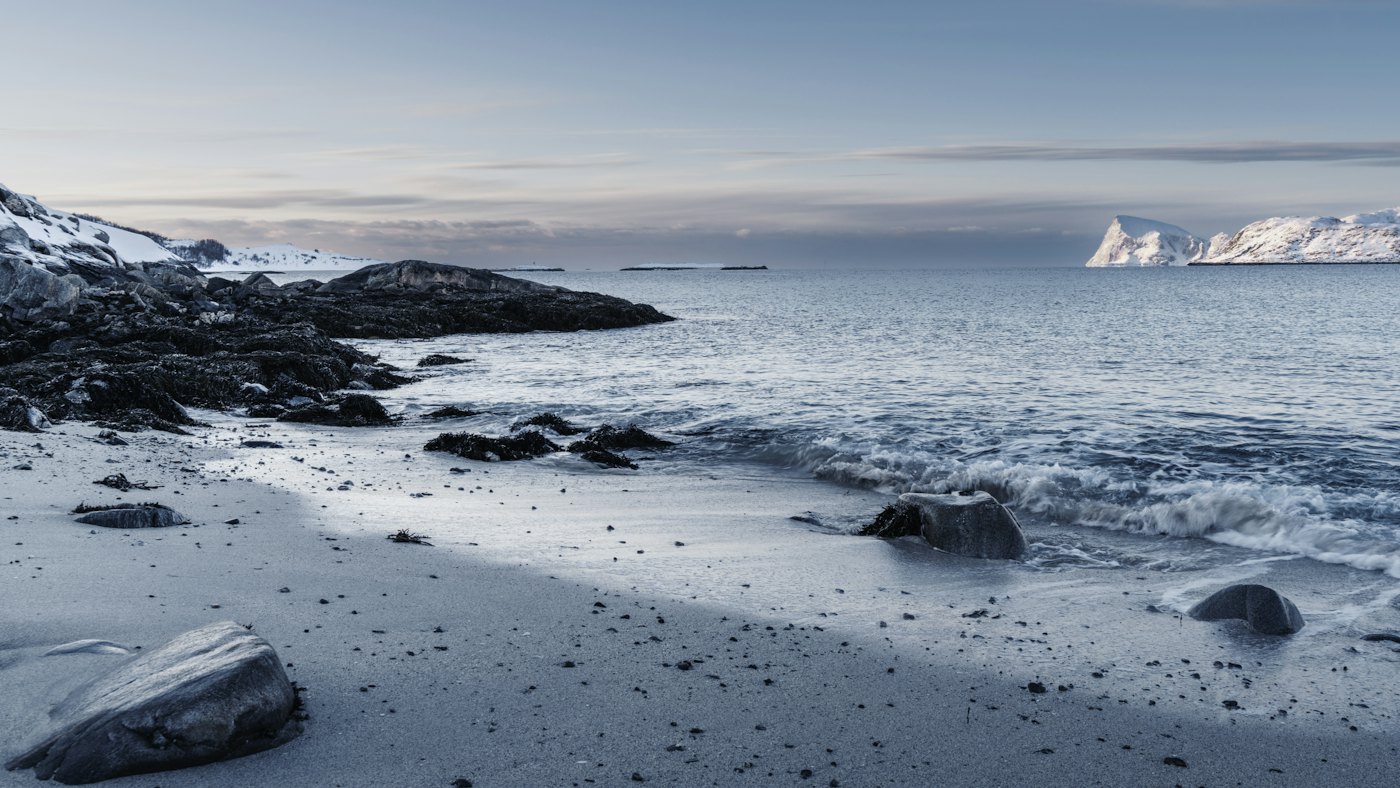 Snow-dusted white sand beach and clear Arctic water at Sommarøy